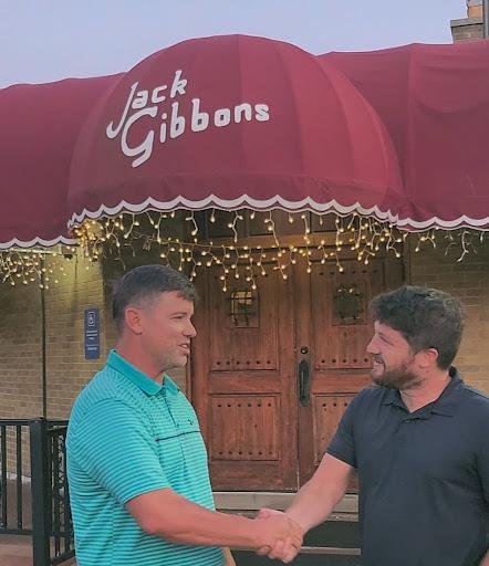 Matthew Gallagher shaking hands with a client outside a restaurant entrance
